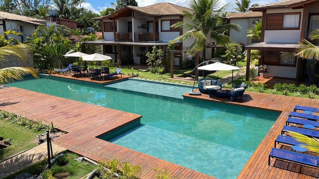 a pool with chairs and umbrellas next to a house at Villaggio Super Aconchegante in Marau