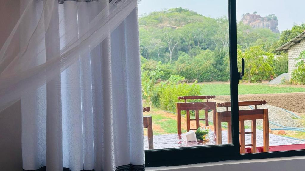 Una ventana con vista a una mesa y sillas. en Sigiri Rock View Lodge, en Sigiriya