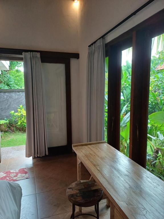 comedor con mesa de madera y ventanas grandes en Green Bowl Bali Guest house, en Ungasan