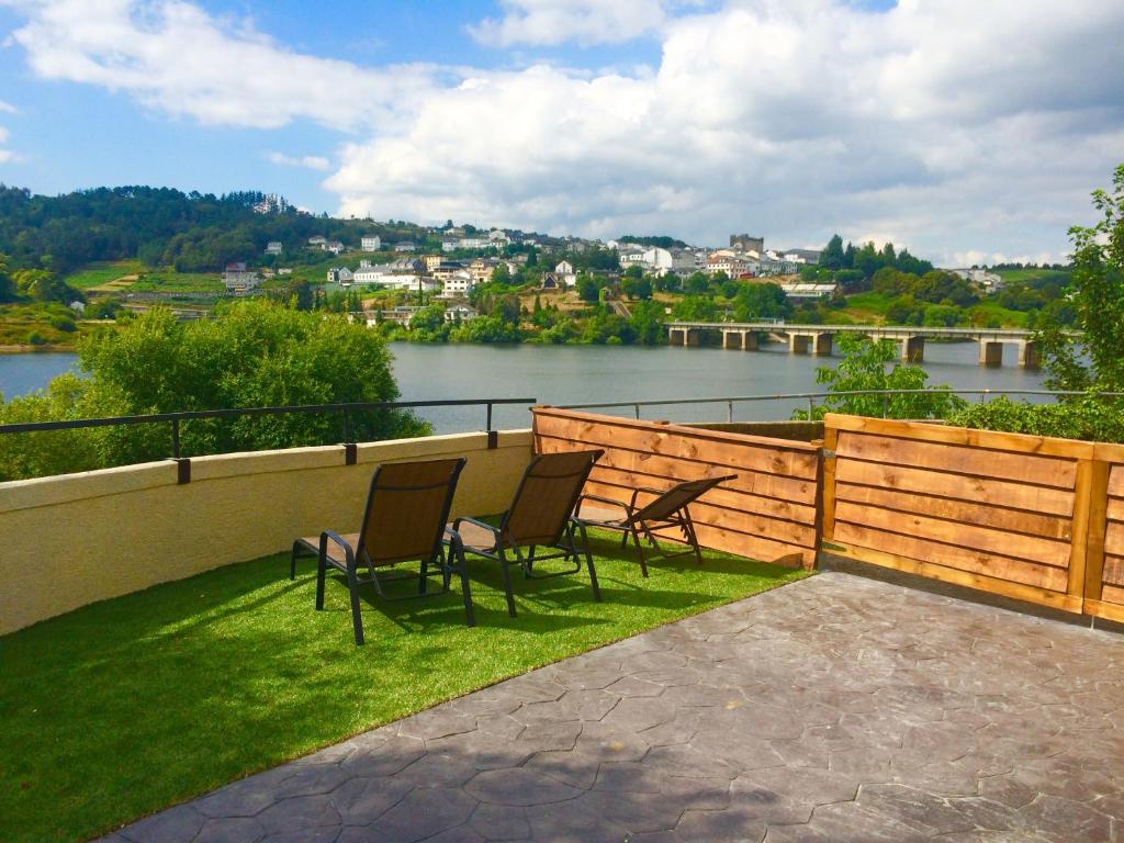 a patio with chairs and a view of a river at A Fontana de Luxo Apartamentos in Portomarin
