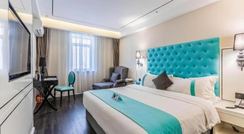 a hotel room with a large bed with a blue headboard at Xana Lite Shenyang Beiling Park Liaoning Building Branch in Shenyang