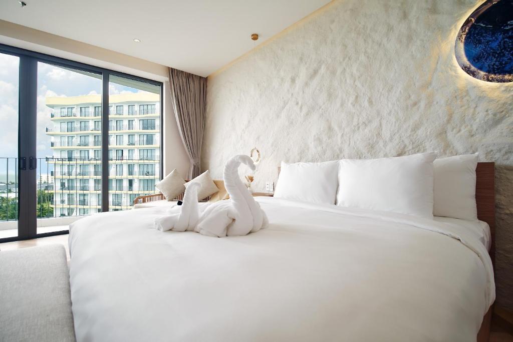 un dormitorio con una gran cama blanca con cisnes. en Hoi An Mona Royal Hotel, en Hà My Tây (2)
