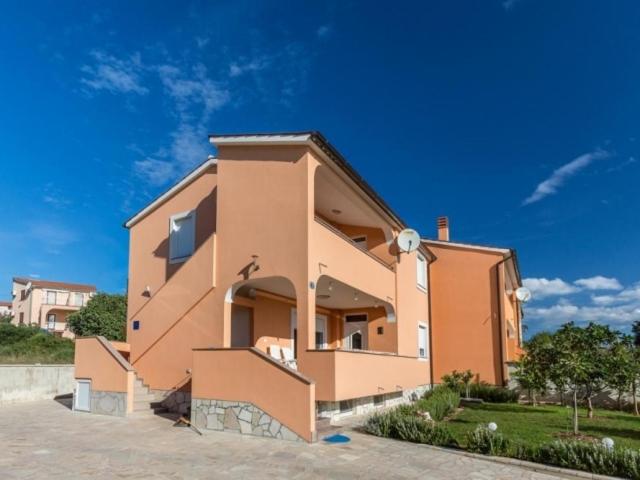 a large orange house with a sky in the background at Apartment Dragica in Ližnjan