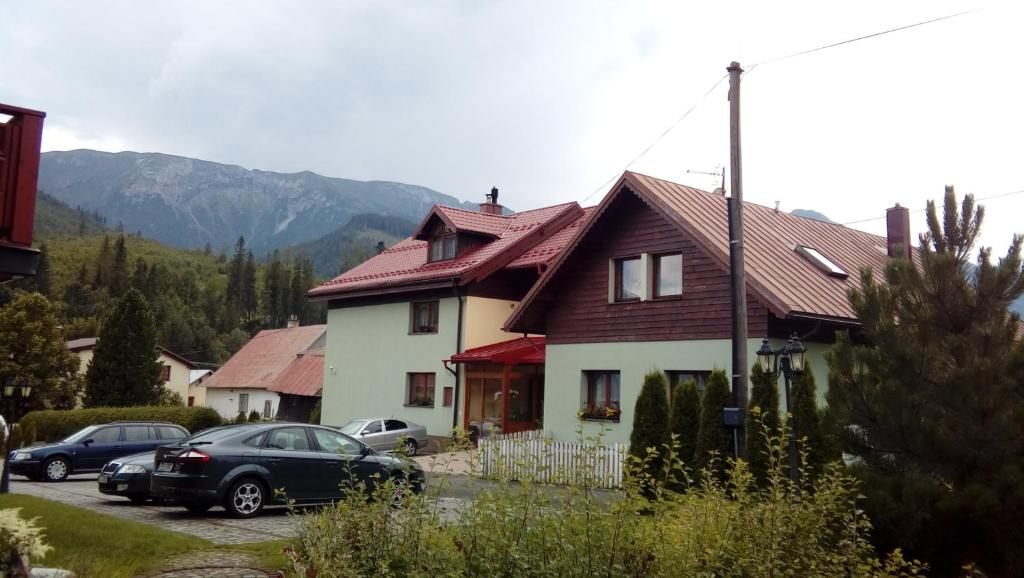 a house with cars parked in a parking lot at Penzión U Aleny in Ždiar