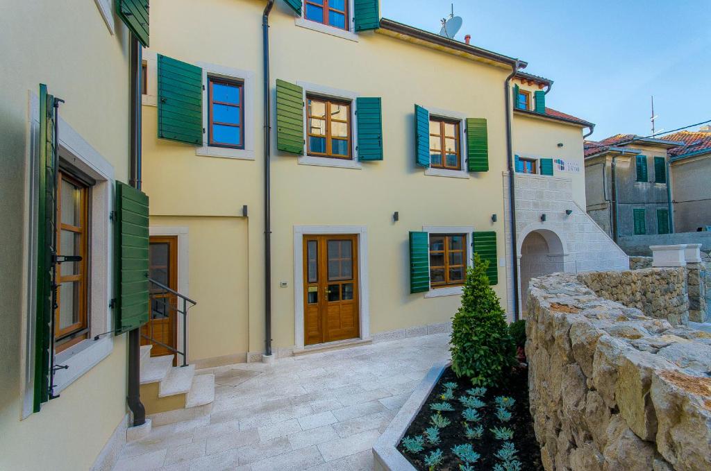 a house with green shutters and a stone wall at Hostel Dvor in Split