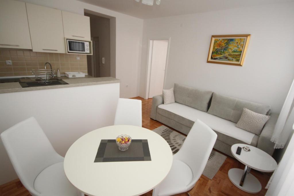 a kitchen and a living room with a white table and chairs at Apartment Harmony in Višegrad