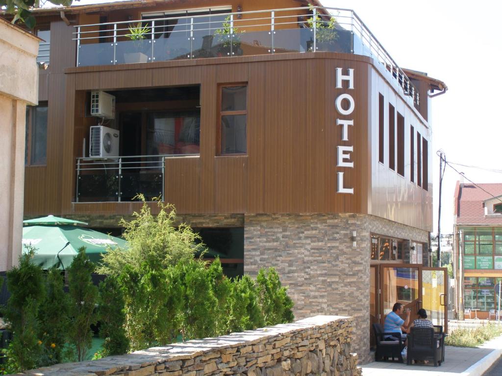 two people sitting on a bench in front of a building at Guesthouse Avenue in Kirkovo