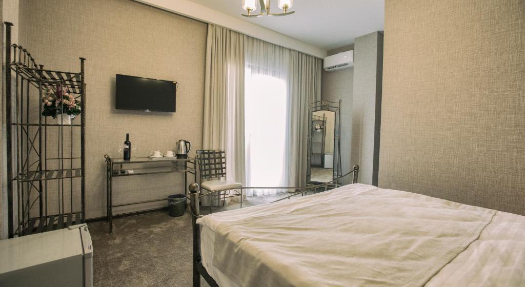 a bedroom with a bed and a tv on the wall at Golden Nugget Tbilisi in Tbilisi City