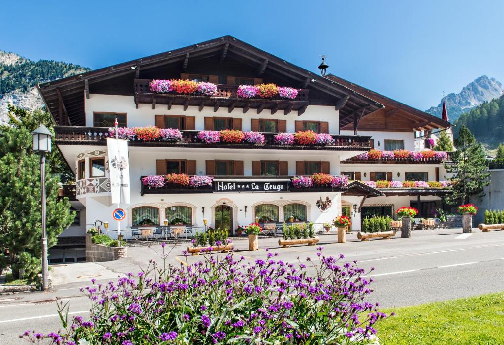 duży budynek z kwiatami przed nim w obiekcie La Truga w mieście Selva di Val Gardena