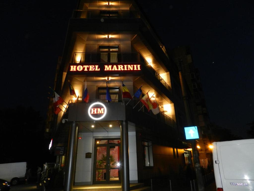 a hotel martini sign in front of a building at night at Hotel Marinii in Bucharest