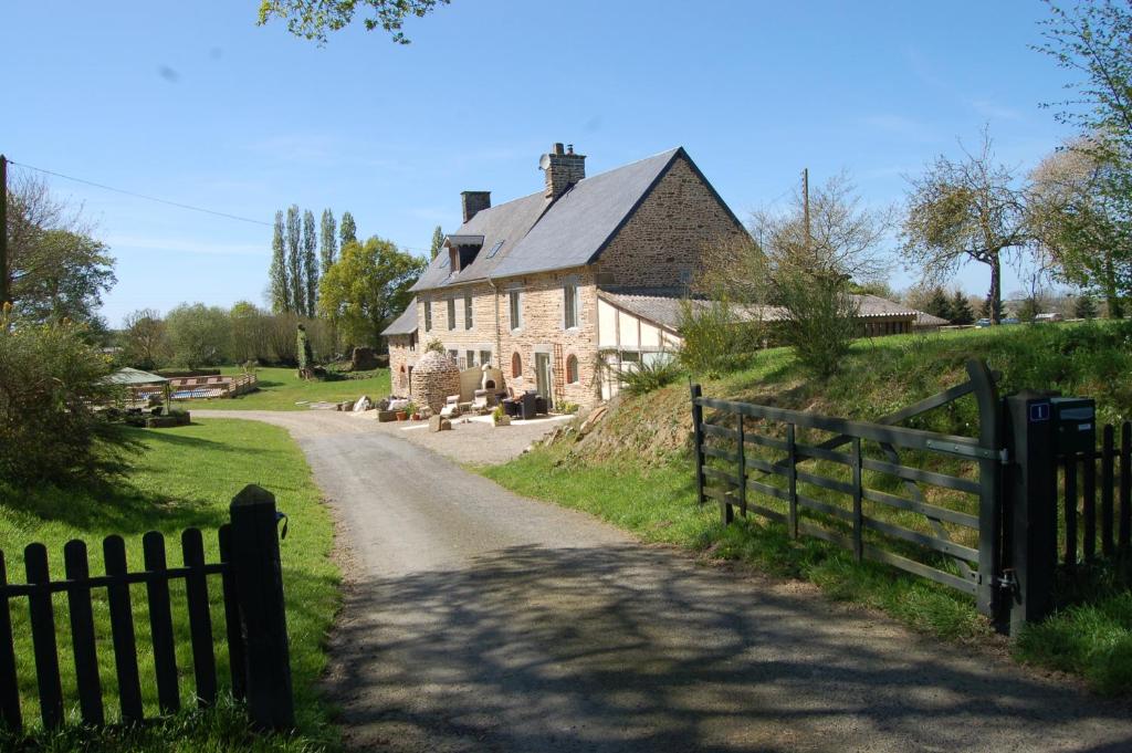 une vieille maison avec une clôture à côté d'un chemin de terre dans l'établissement Bijoux Gite, à Argouges