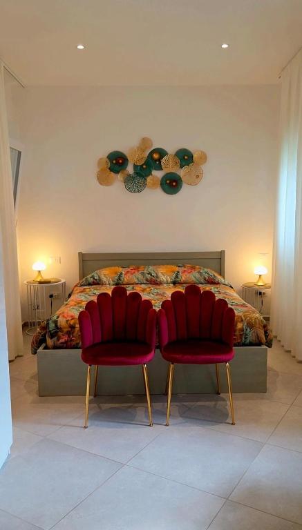 two red chairs sitting in front of a bed at Appartamento Teodorico Ravenna in Ravenna