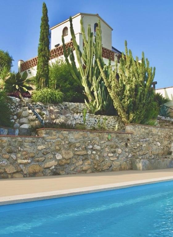 a house with a retaining wall next to a swimming pool at Torre Costa Brava Private pool in Garrigás