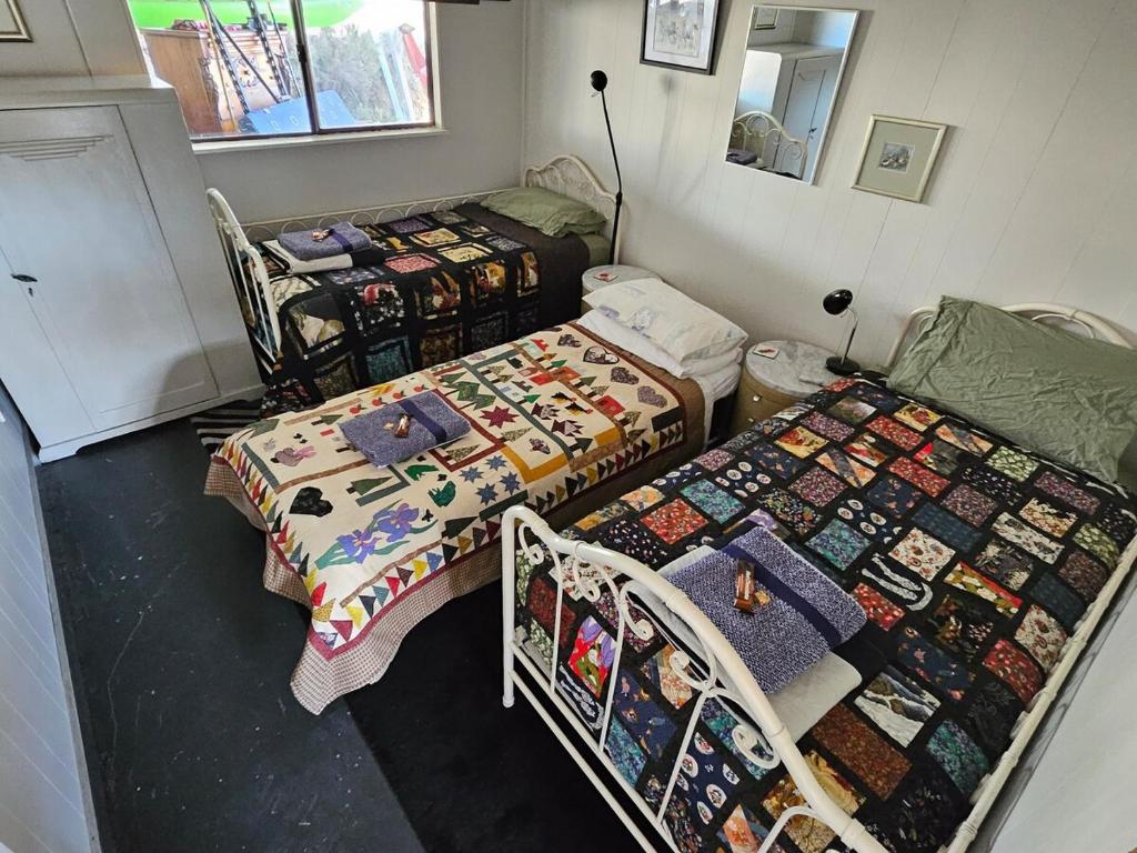 2 camas en una habitación con edredones en The Shed, en Cooma