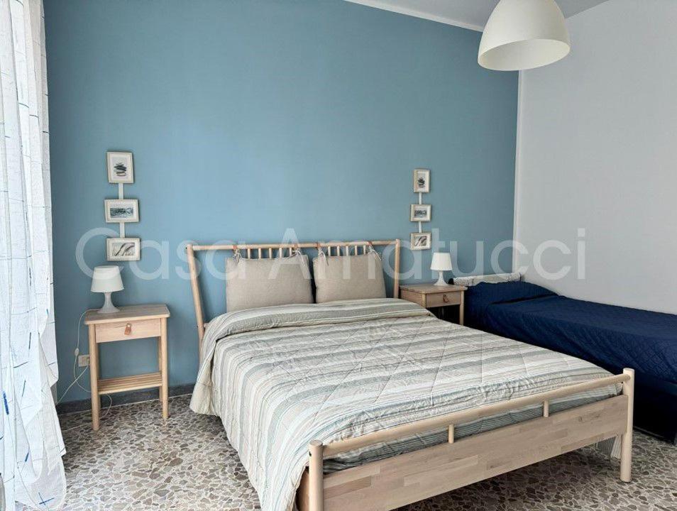 a bedroom with a blue wall with a bed and two tables at Casa Amatucci in Santa Maria di Castellabate
