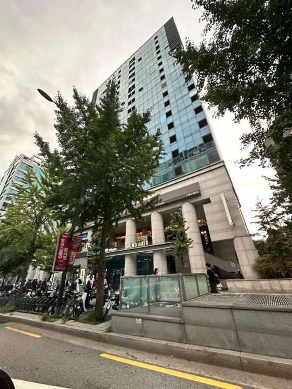 Un edificio alto con un árbol delante. en CHACHA LATTE Hongdae Apartment 1min to station 弘大 ホンデ, en Seúl