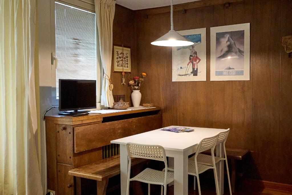 a dining room with a white table and a television at Casa Elena in Breuil-Cervinia