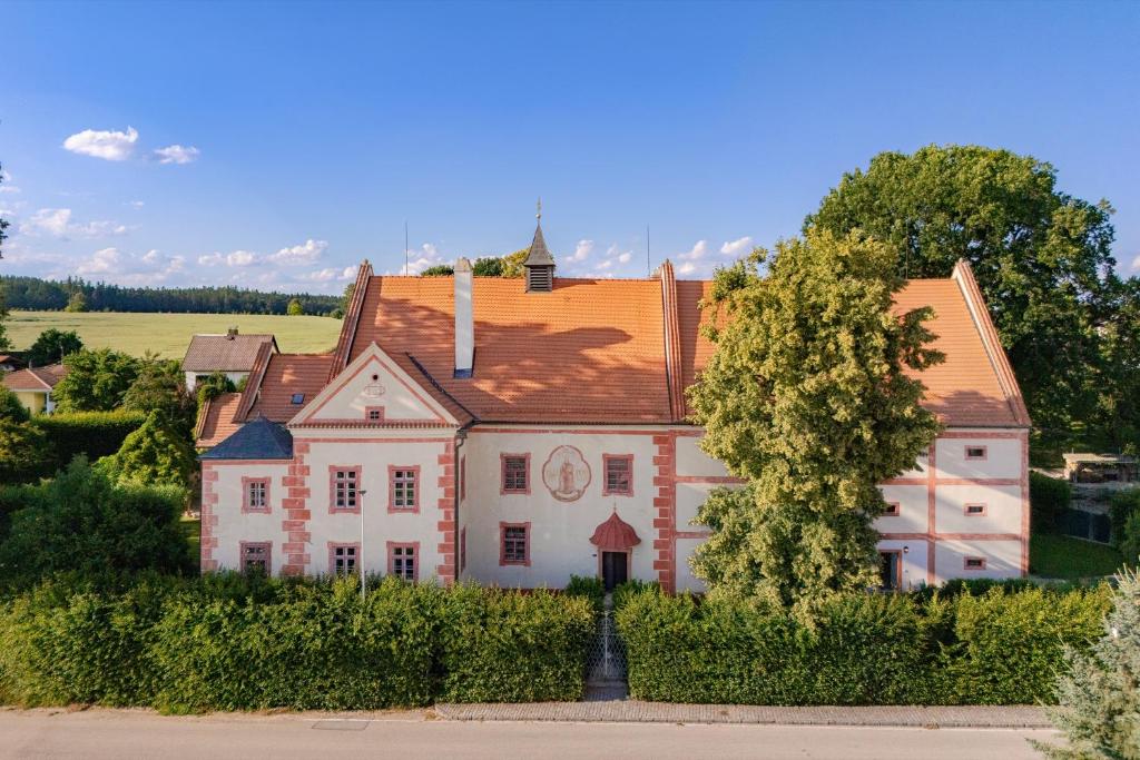 Una casa vieja con un árbol delante. en Zámek Ostrolov, en Ostrolovský Újezd