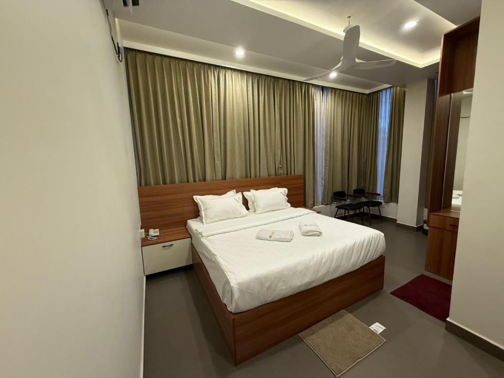 マイソールにあるHotel Diyanviの白いシーツが敷かれた大きなベッドのある寝室
