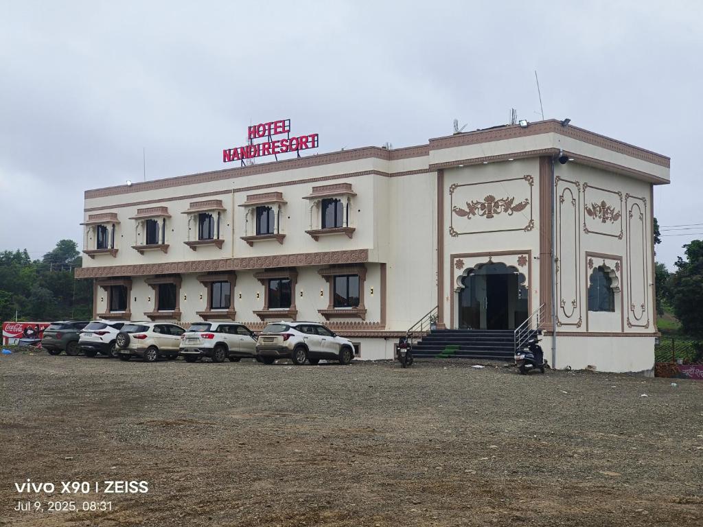 a building with cars parked in front of it at Hotel Nandi Resort in Jiwājīnagar