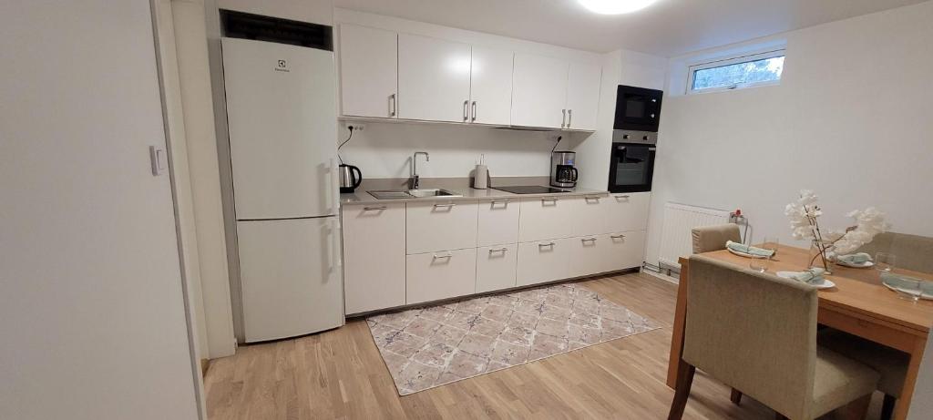 a kitchen with white cabinets and a wooden table and a dining room at Modern apartment near Volvo Cars in Torslanda
