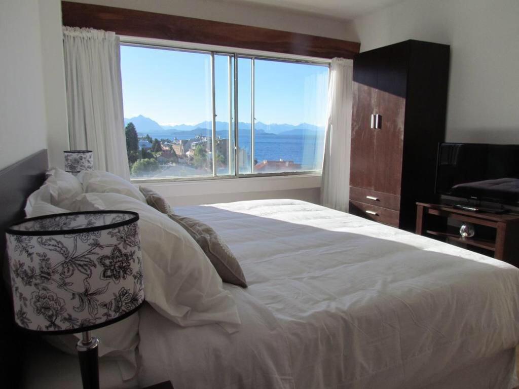 une chambre avec un grand lit avec une grande fenêtre dans l'établissement Costa Nahuel Apartments 1, à San Carlos de Bariloche