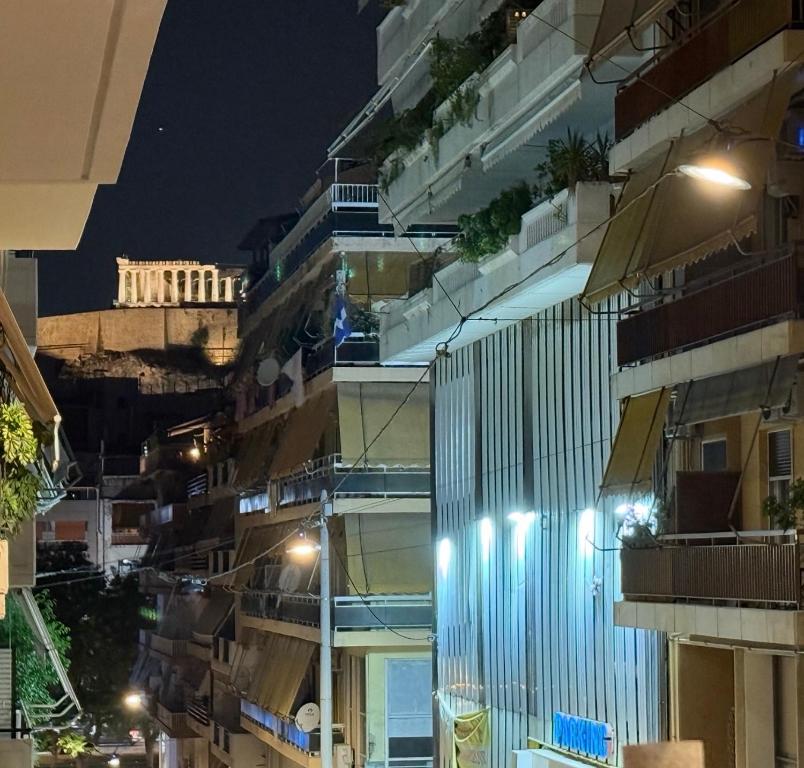 a building with lights on the side of it at night at Acropolis Path - Elegant Apartment near Plaka in Athens