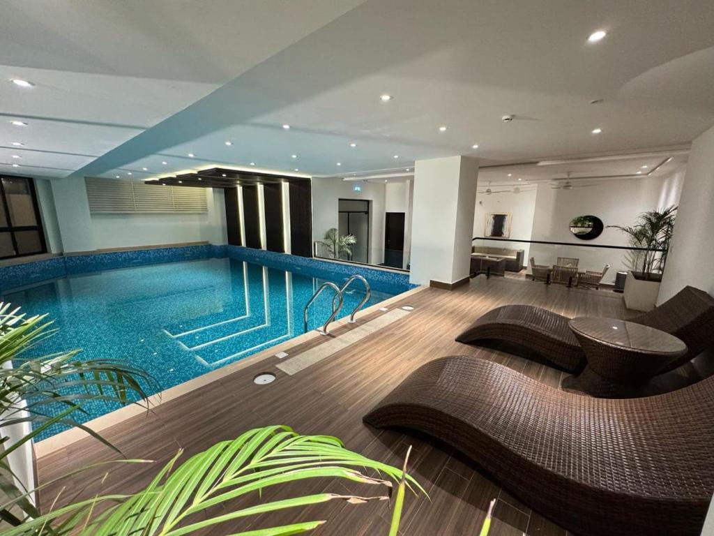 a swimming pool with chairs and a table in a building at Gulberg-Zameen Aurum starlit-Gym in Lahore