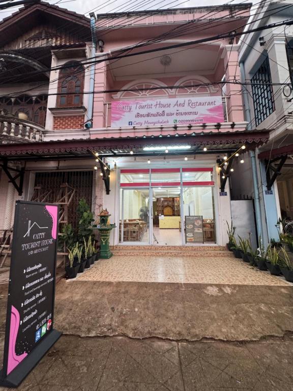 a pink building with a sign in front of it at Catty tourist house in Thakhek