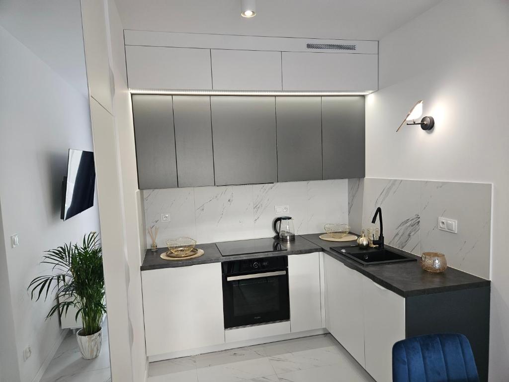 une cuisine blanche avec un évier et une cuisinière dans l'établissement Apartamenty Szafir Let's Sea Gąski, à Gąski