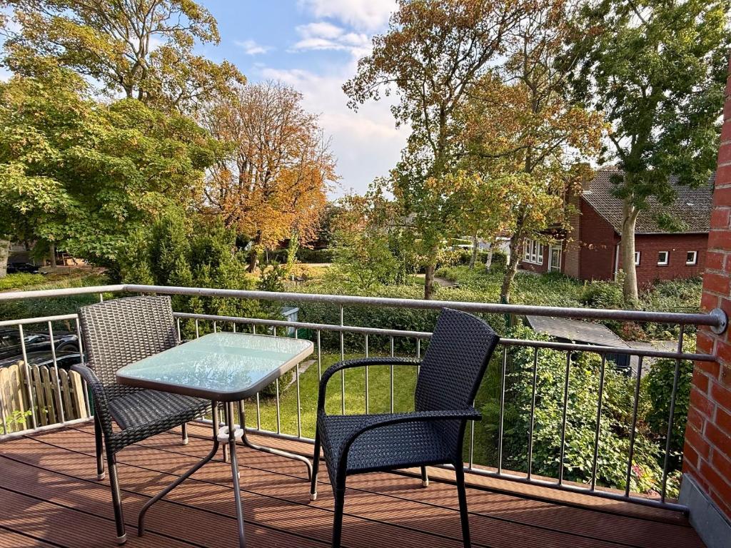 a patio with two chairs and a table on a balcony at Nordlicht in Krummhörn