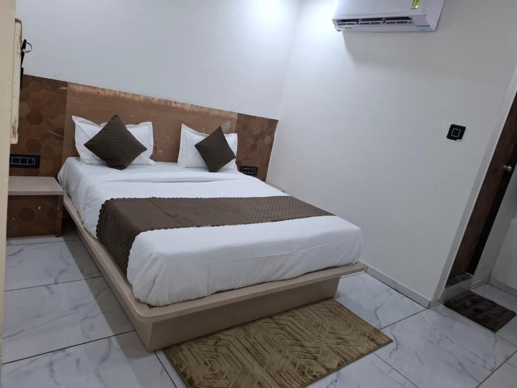 a bedroom with a bed with white sheets and pillows at Hotel Asiana Randheja Gandhinagar in Gandhinagar