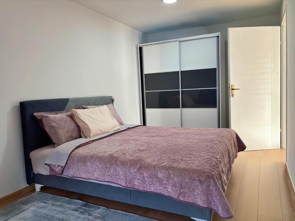 a bedroom with a bed with a purple comforter at Sanlej Apartman in Tuzla