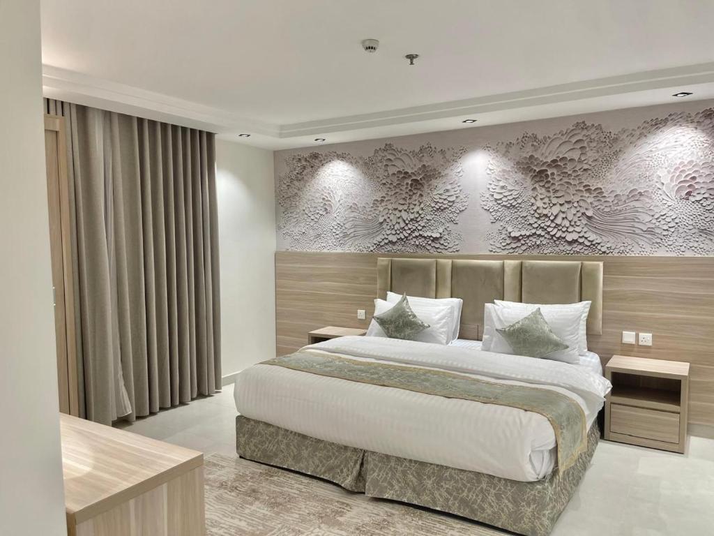 a bedroom with a large bed and a wall with flowers at Burj Al Hayat Furnished Apartment - Jazan in Jazan