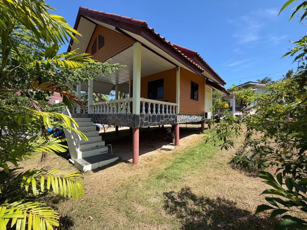 una pequeña casa amarilla con porche y patio en Chill House, en Ko Pha Ngan