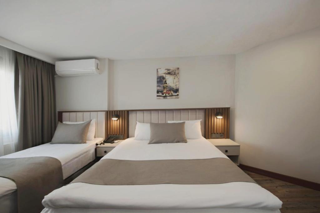 Dos camas en una habitación de hotel con paredes blancas. en Hotel Öncü, en Estambul