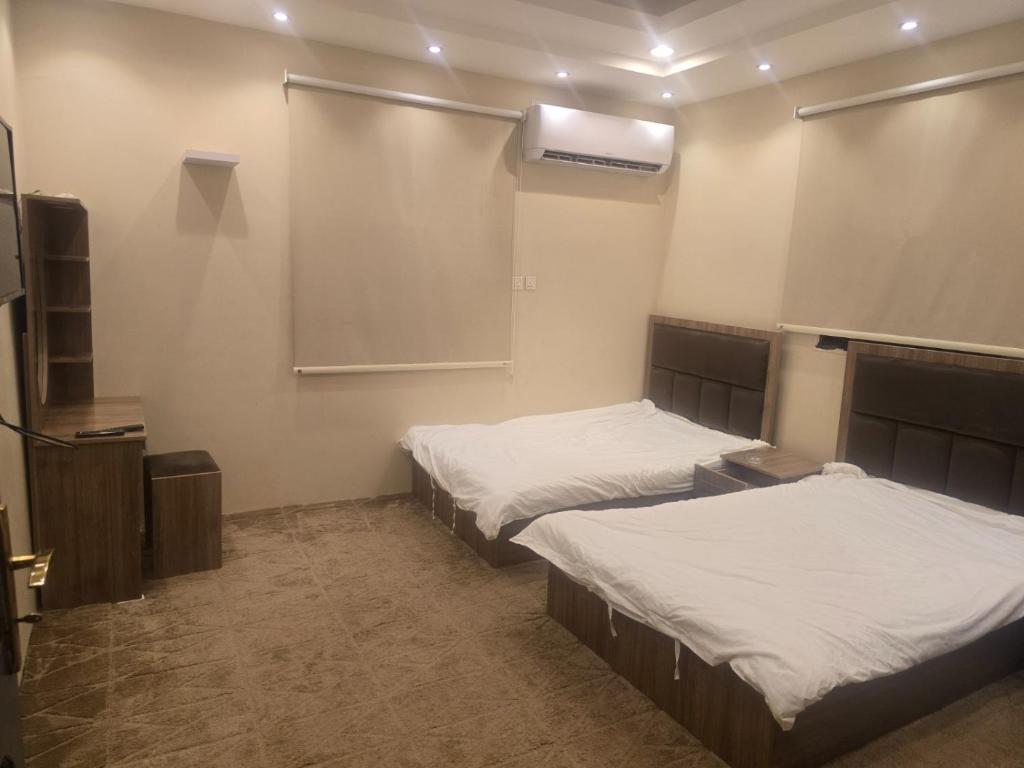 una habitación con dos camas y una pantalla de proyección en Marasi, en Al Ula