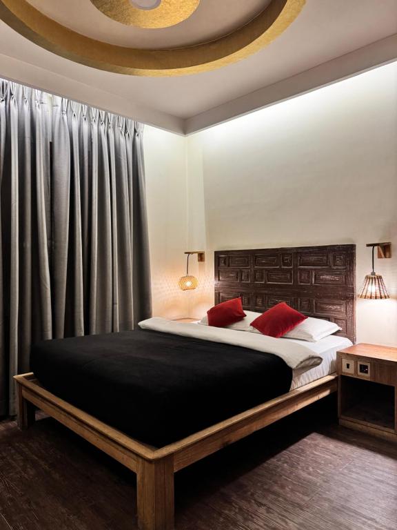 a bedroom with a large bed with red pillows at La plaza in Pātan