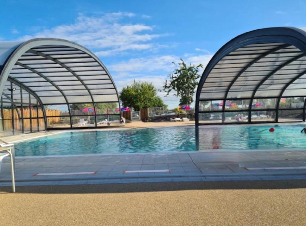 a swimming pool in a building with two gates at L'Eleganzia Piscines et nature en Normandie in Litteau