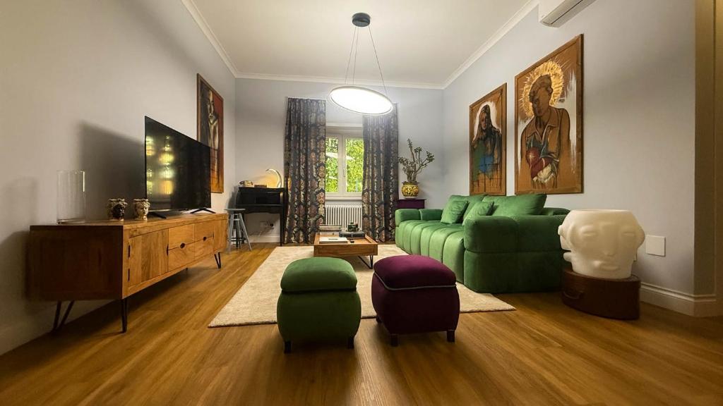 un soggiorno con divano verde e ottomana di The House of Janus Luxury & Design Stay near Rome a Ciampino