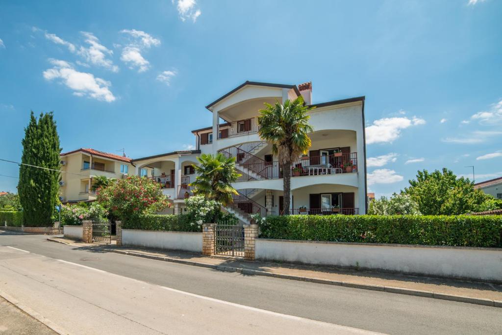 a building with a palm tree in front of a street at Guest House Marica in Rovinj