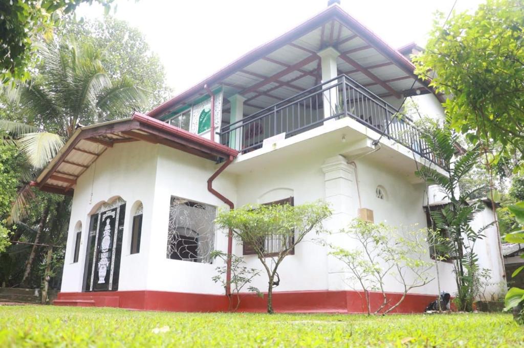 Una casa blanca con un balcón encima. en Aluth Gedara Villa, en Talpe