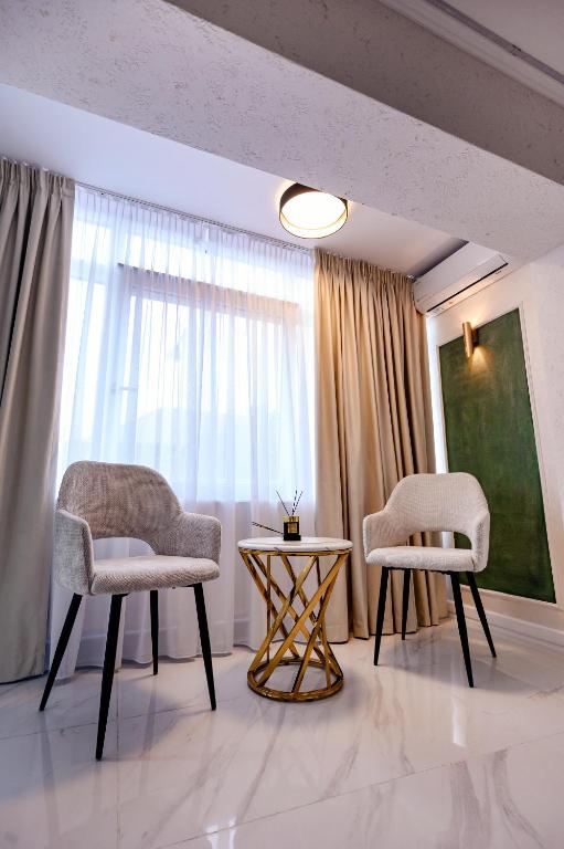 two chairs and a table in a room with a window at Luxury House in Drăgăşani