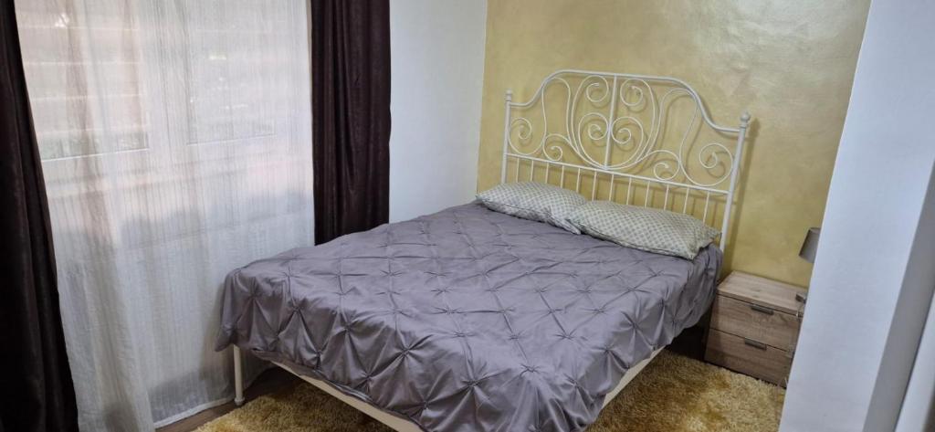 1 dormitorio con 1 cama con edredón morado y ventana en LCB Apartments GM01, en Târgu Mureș