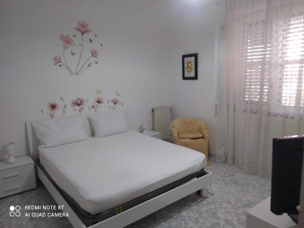 a white bedroom with a bed and a chair at PM 698 Via Fuscillo in Mattine