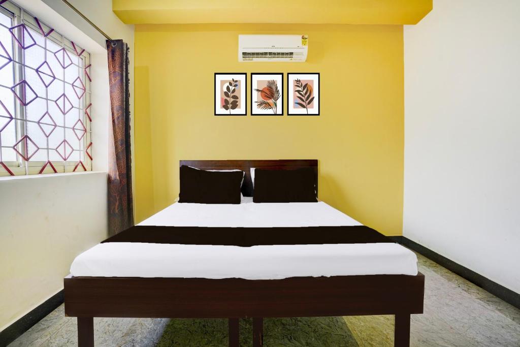 a bed in a room with a yellow wall at Hotel O Shalom home stay in Goa