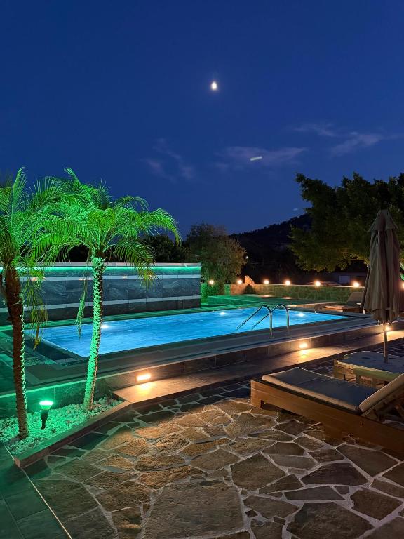 a swimming pool with palm trees and lights at night at Casa Loma 2 RHODES-FAMILY VILLA,PRIVATE POOL & FARM in Rhodes Town