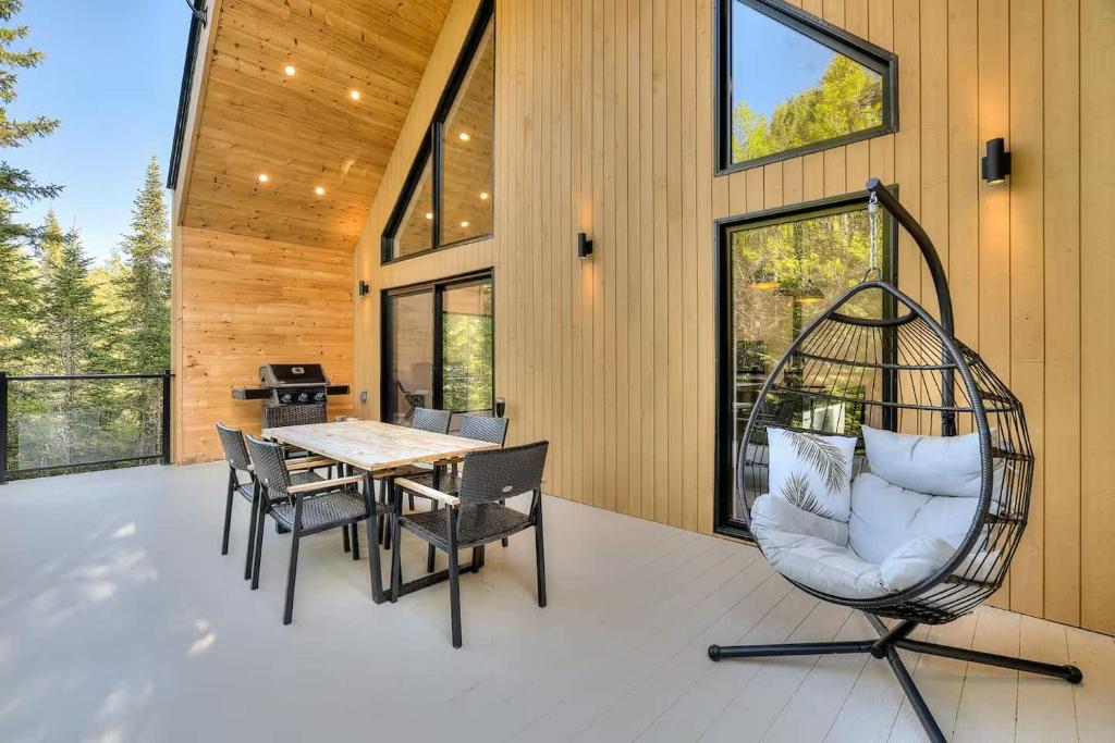 een veranda met een schommel en een tafel en stoelen bij Oslo Scandinavian Getaway Spa & Pet-Friendly in Saint Come
