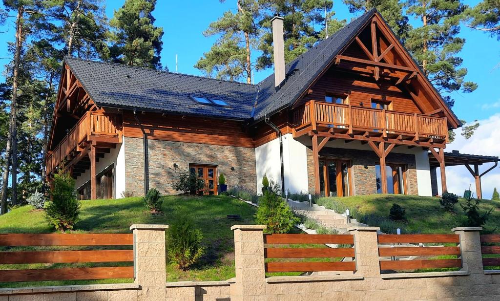 una casa de troncos con porche y valla de madera en Villa Viktoria, en Hamr na Jezeře