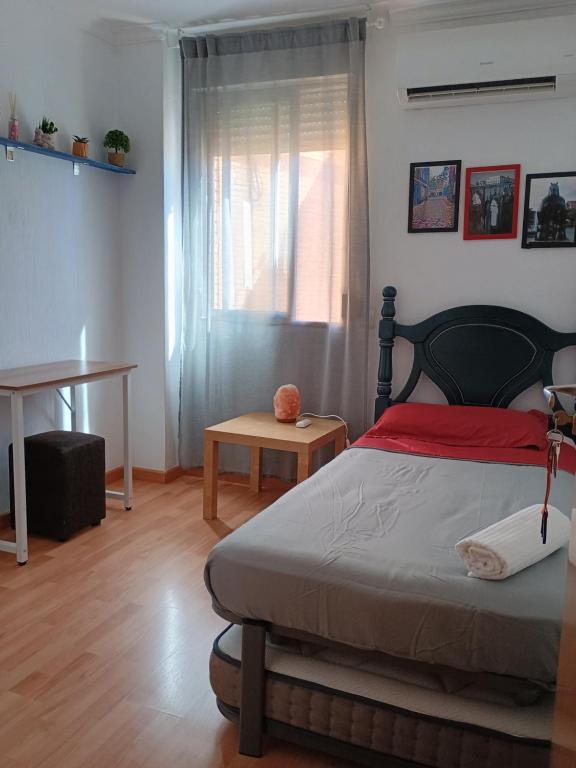 a bedroom with a bed and a table and a window at Tu Hogar en Ronda in Ronda